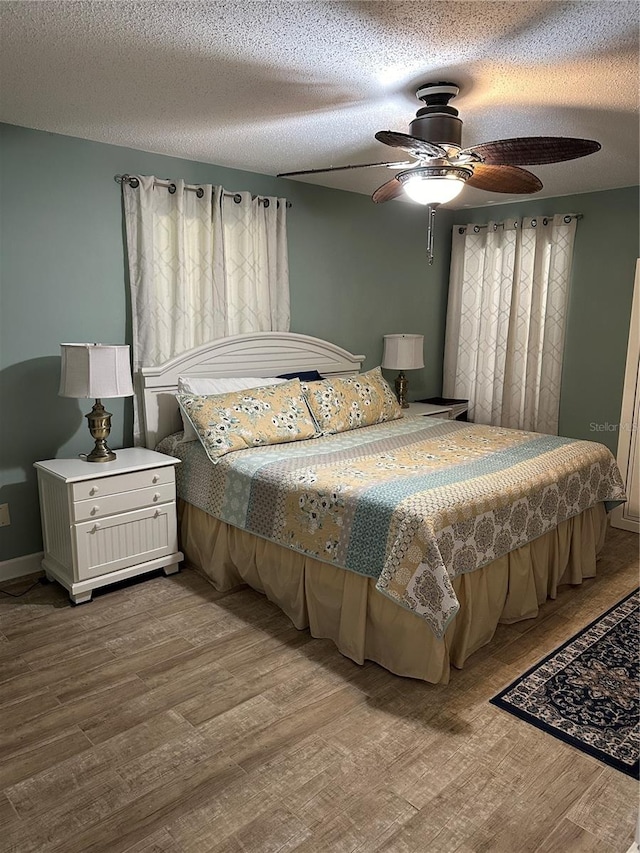 bedroom with a textured ceiling, ceiling fan, and light wood-type flooring