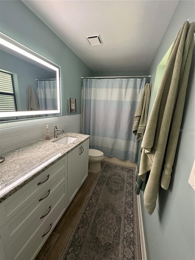 bathroom with toilet, tasteful backsplash, hardwood / wood-style floors, and vanity