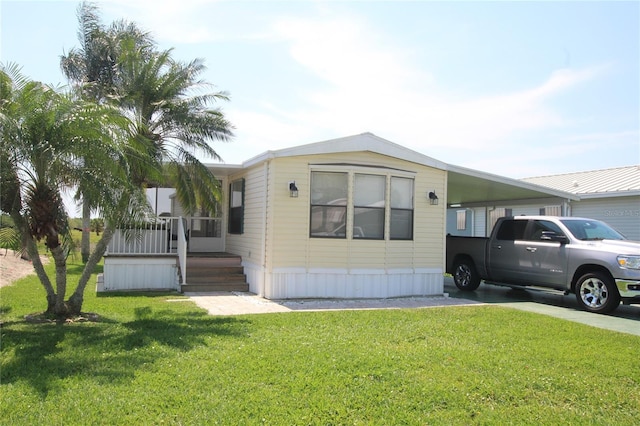 manufactured / mobile home with a carport and a front yard