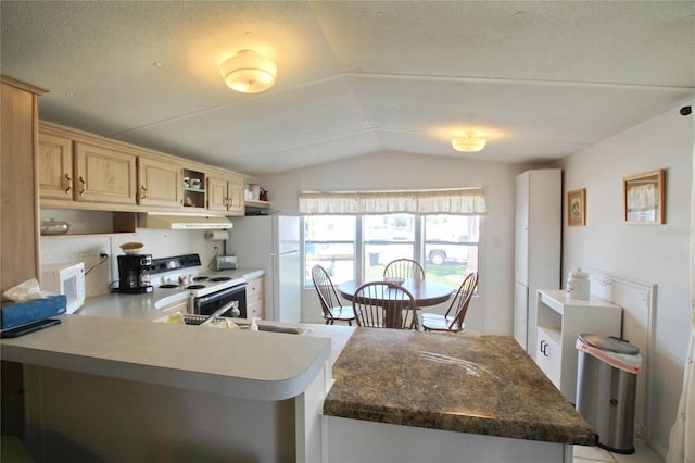 kitchen with light brown cabinets, vaulted ceiling, white appliances, and a textured ceiling