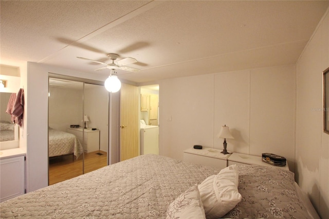 bedroom with ceiling fan, ensuite bathroom, washing machine and clothes dryer, a textured ceiling, and hardwood / wood-style flooring