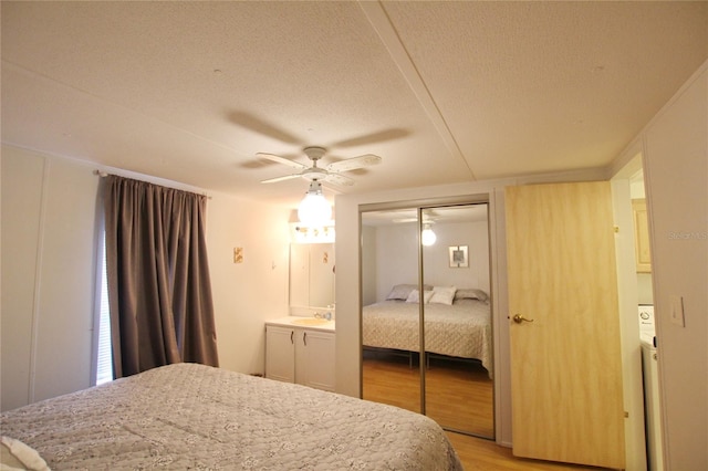 bedroom featuring light hardwood / wood-style floors, a closet, ceiling fan, a textured ceiling, and sink