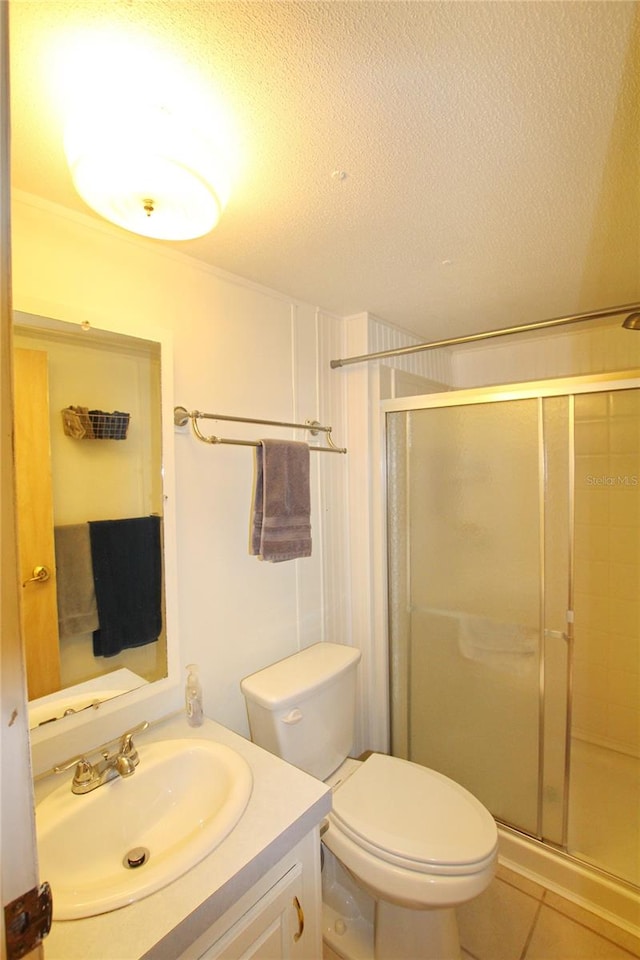 bathroom featuring tile flooring, a shower with door, a textured ceiling, toilet, and vanity