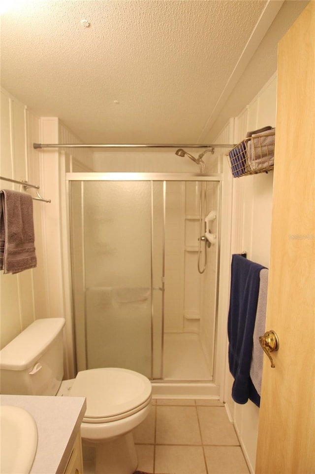 bathroom with toilet, a shower with door, tile floors, a textured ceiling, and vanity