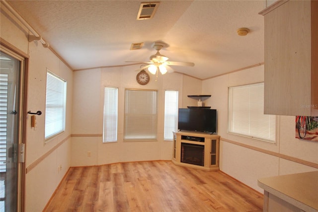 unfurnished living room featuring vaulted ceiling, ceiling fan, light hardwood / wood-style floors, and a textured ceiling