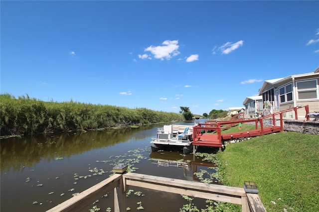 view of dock with a yard and a deck with water view