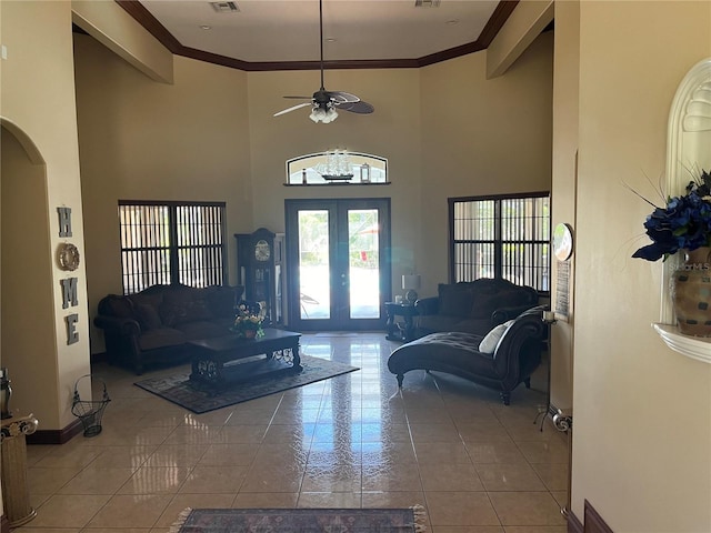 tiled living room featuring ornamental molding, a towering ceiling, ceiling fan, and french doors