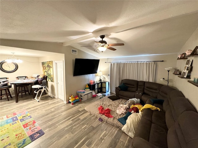 living room featuring hardwood / wood-style floors, lofted ceiling with beams, ceiling fan with notable chandelier, and a textured ceiling