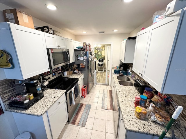 kitchen featuring backsplash, white cabinets, sink, light stone countertops, and appliances with stainless steel finishes