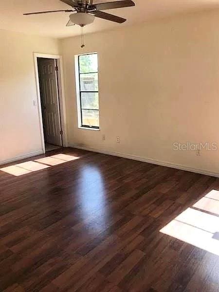 empty room featuring dark hardwood / wood-style flooring and ceiling fan