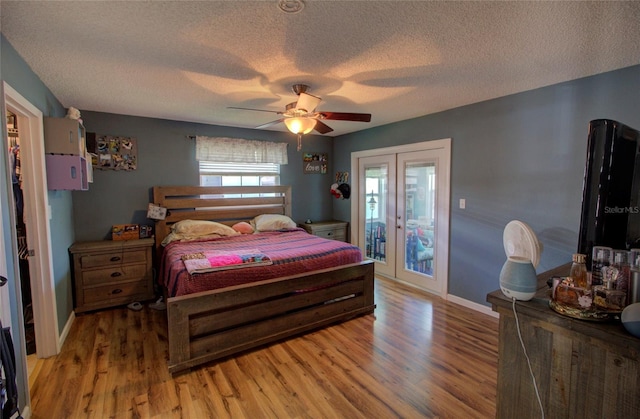 bedroom with wood-type flooring, access to outside, ceiling fan, a textured ceiling, and french doors