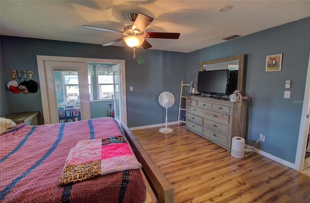 bedroom with ceiling fan, light hardwood / wood-style flooring, and a textured ceiling