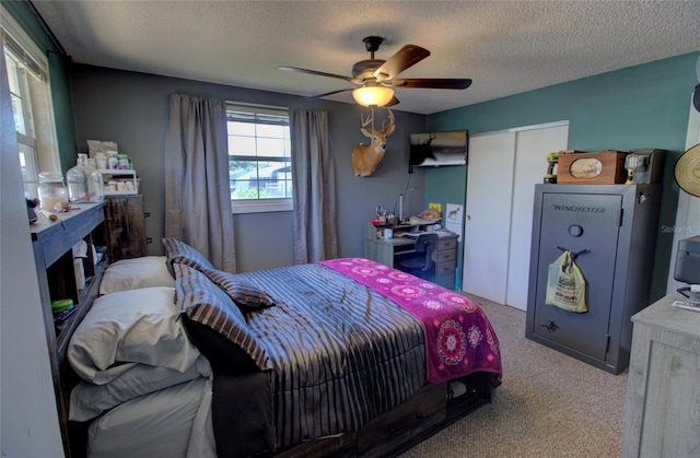 carpeted bedroom featuring ceiling fan, a closet, and a textured ceiling