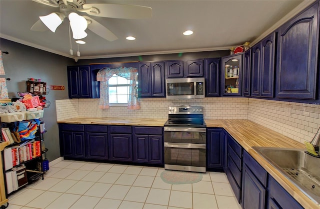 kitchen with blue cabinets, appliances with stainless steel finishes, light tile patterned floors, and wood counters