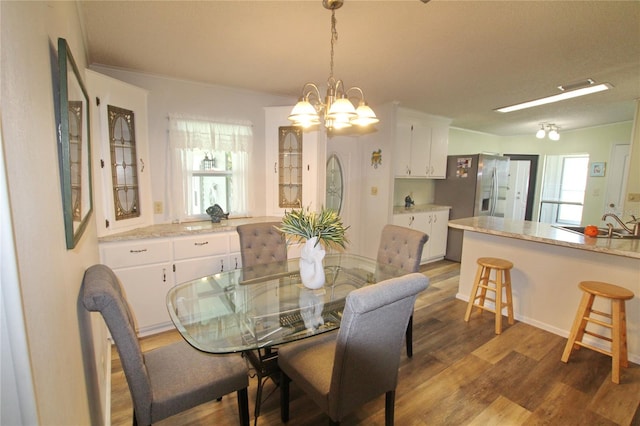 dining area with ornamental molding, sink, hardwood / wood-style floors, and a chandelier