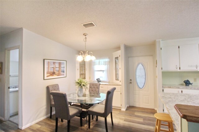 dining room featuring wood-type flooring, a chandelier, and a textured ceiling