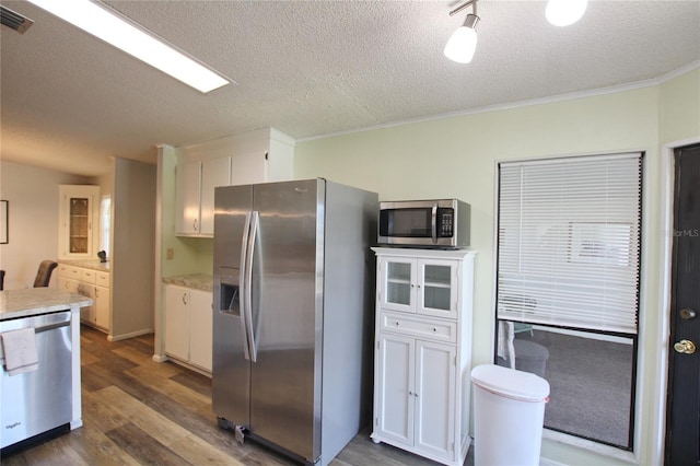 kitchen with appliances with stainless steel finishes, a textured ceiling, dark hardwood / wood-style flooring, and white cabinets