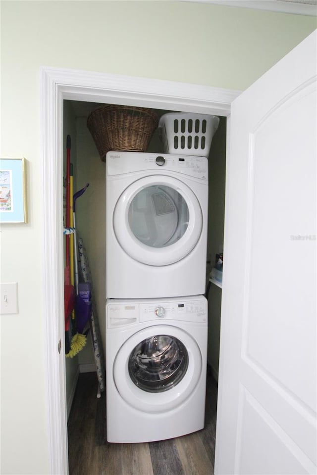 laundry area featuring dark wood-type flooring and stacked washer / dryer