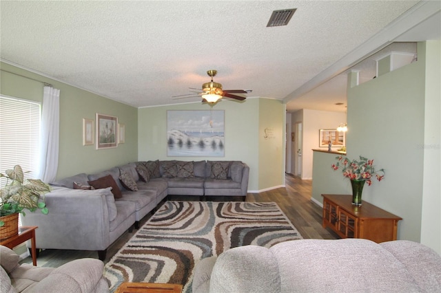 living room with a textured ceiling, ceiling fan, and dark hardwood / wood-style floors