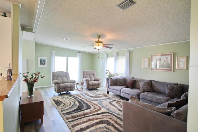 living room featuring ceiling fan, wood-type flooring, crown molding, and a textured ceiling