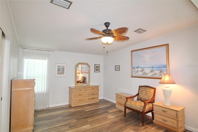 living area with ceiling fan, dark wood-type flooring, and a textured ceiling