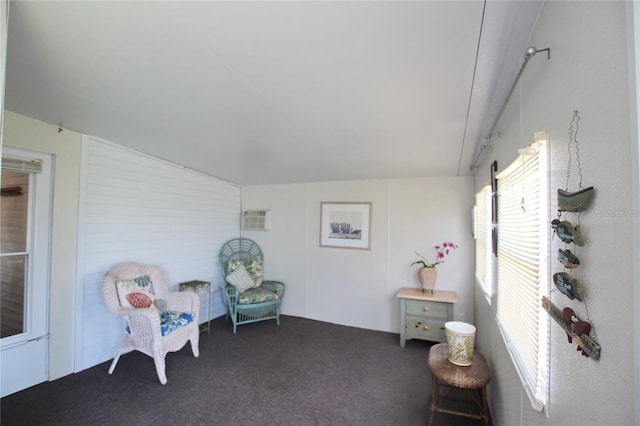 sitting room featuring an AC wall unit, carpet flooring, and lofted ceiling