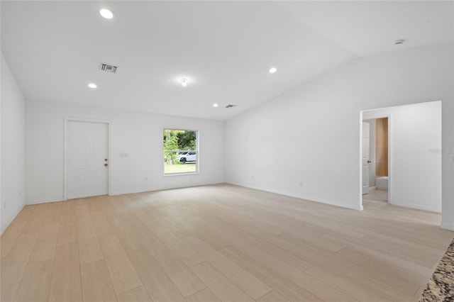 empty room featuring light wood-type flooring and vaulted ceiling