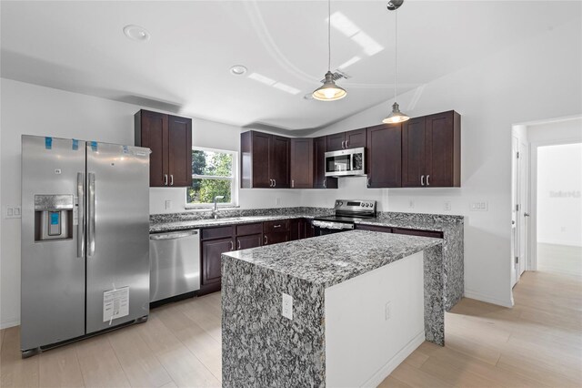 kitchen with decorative light fixtures, stainless steel appliances, sink, vaulted ceiling, and light hardwood / wood-style flooring