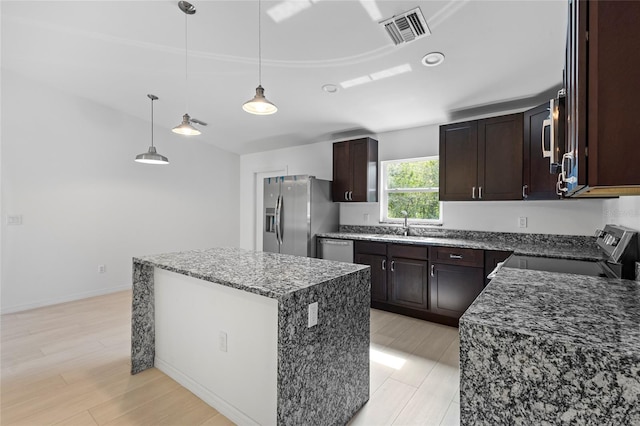 kitchen featuring light hardwood / wood-style flooring, a kitchen island, stainless steel appliances, pendant lighting, and dark brown cabinetry