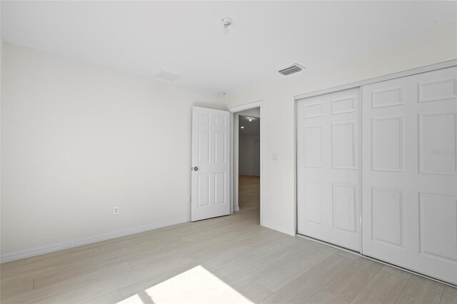 unfurnished bedroom featuring light hardwood / wood-style flooring and a closet