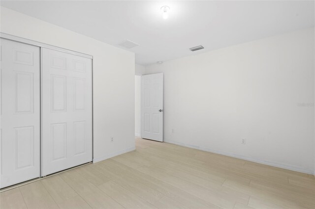 unfurnished bedroom featuring light wood-type flooring and a closet