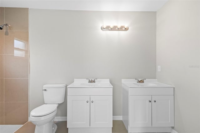 bathroom with tiled shower, vanity, tile patterned flooring, and toilet