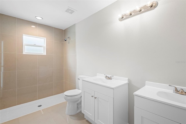 bathroom with tile patterned floors, vanity, tiled shower, and toilet