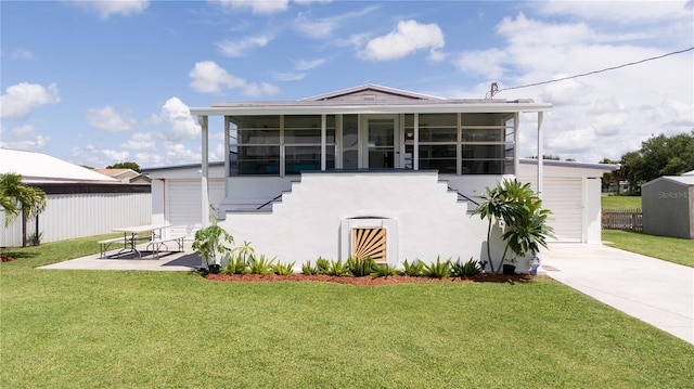 view of front of property featuring a garage, a front lawn, and a sunroom