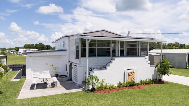 view of front of home with a sunroom, a garage, a patio, and a front yard