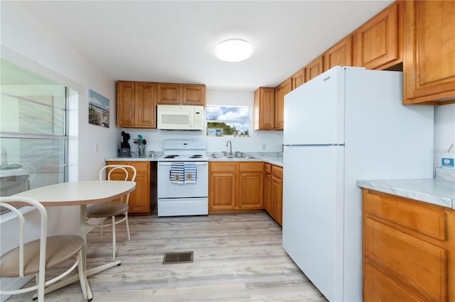 kitchen with white appliances, sink, and light hardwood / wood-style flooring