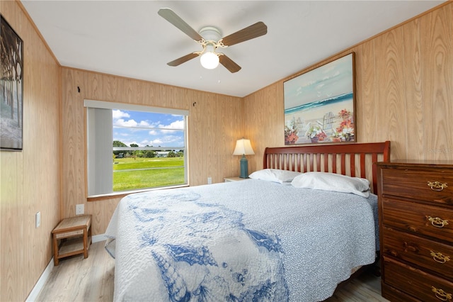 bedroom featuring ceiling fan, wood walls, and wood-type flooring