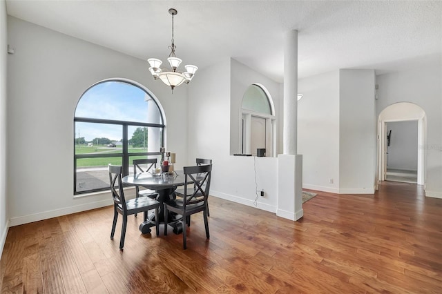 dining space with a notable chandelier, a textured ceiling, and hardwood / wood-style flooring