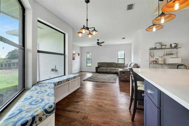 interior space featuring a textured ceiling, ceiling fan with notable chandelier, and dark wood-type flooring