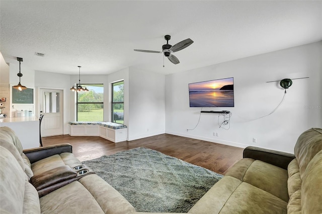 living room with a textured ceiling, ceiling fan with notable chandelier, and dark hardwood / wood-style floors