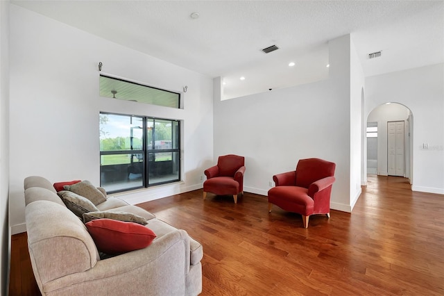 living room with a textured ceiling, a high ceiling, and hardwood / wood-style floors