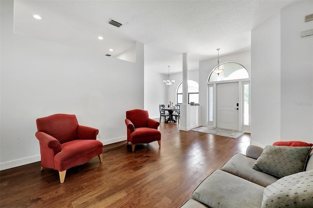 living room with a textured ceiling, dark hardwood / wood-style flooring, and a notable chandelier