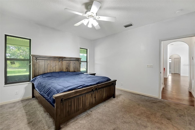 carpeted bedroom featuring a textured ceiling and ceiling fan