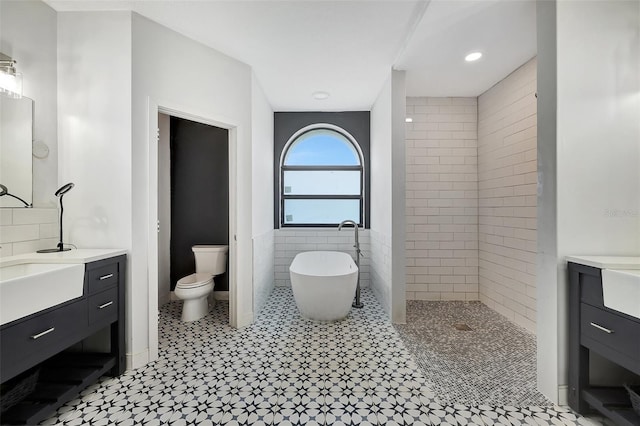 full bathroom featuring tile walls, separate shower and tub, vanity, and toilet