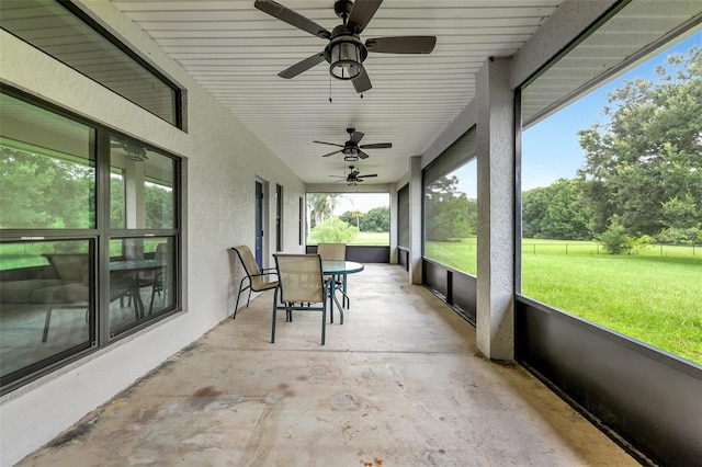 unfurnished sunroom featuring ceiling fan