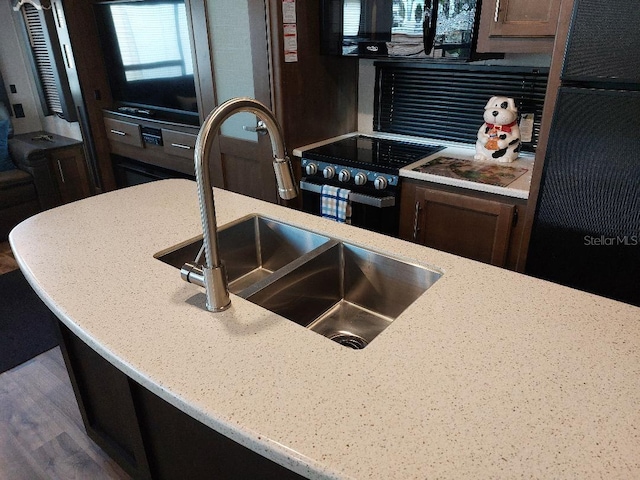 kitchen with light stone counters, sink, and black appliances