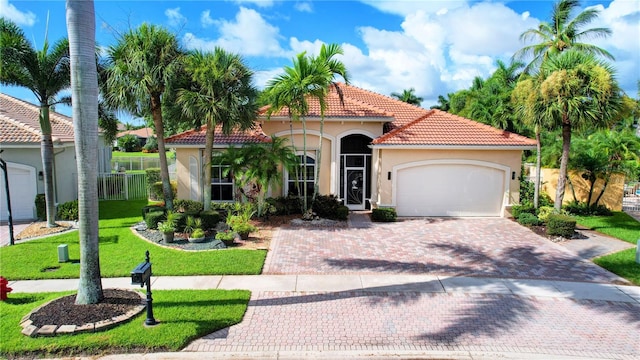 mediterranean / spanish-style house featuring a garage and a front lawn