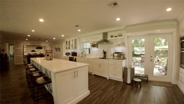 kitchen with a center island, dark wood-type flooring, a breakfast bar, island exhaust hood, and white cabinets