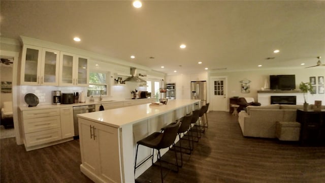 kitchen featuring a breakfast bar area, a center island, stainless steel appliances, dark wood-type flooring, and white cabinetry