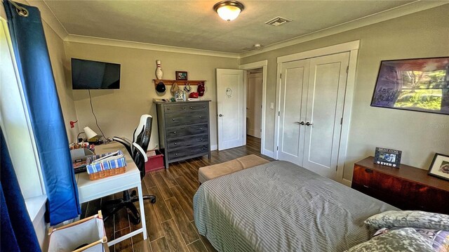 bedroom featuring crown molding, dark hardwood / wood-style flooring, and a closet